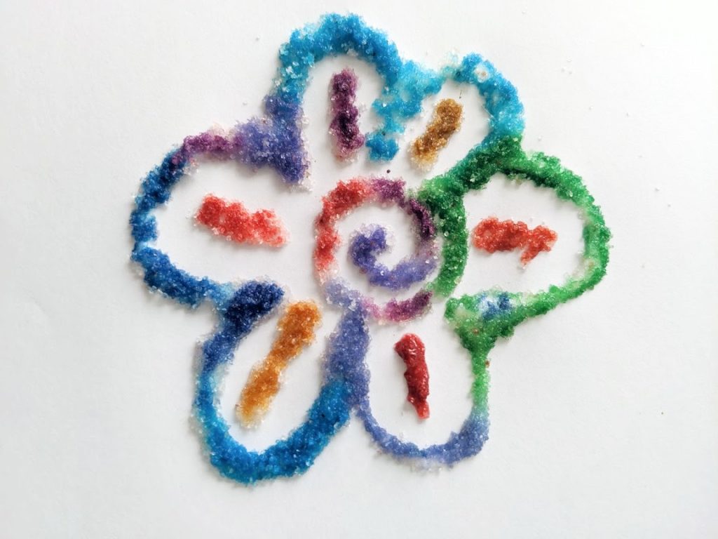 Completed salt art drawing of multicolored flower. 