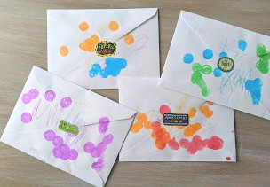 Four envelopes (the backs are pictured) decorated with paint, crayons, and stickers. 