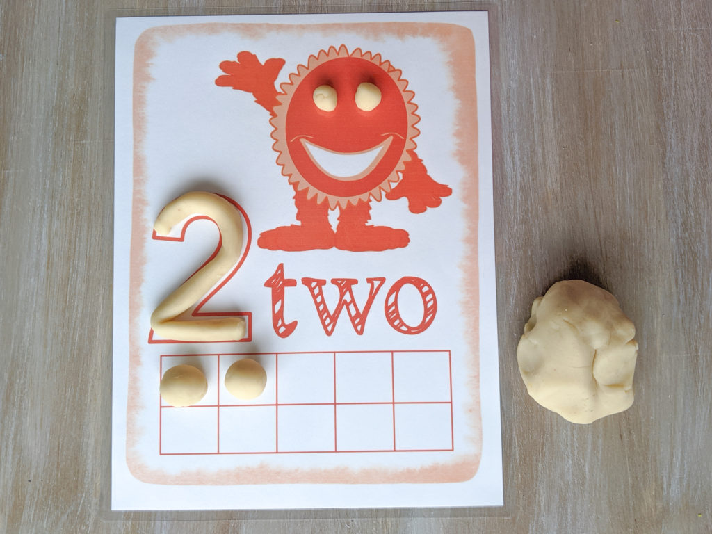 Orange ten frame mat with the number two on it and play dough being used as a manipulative. 